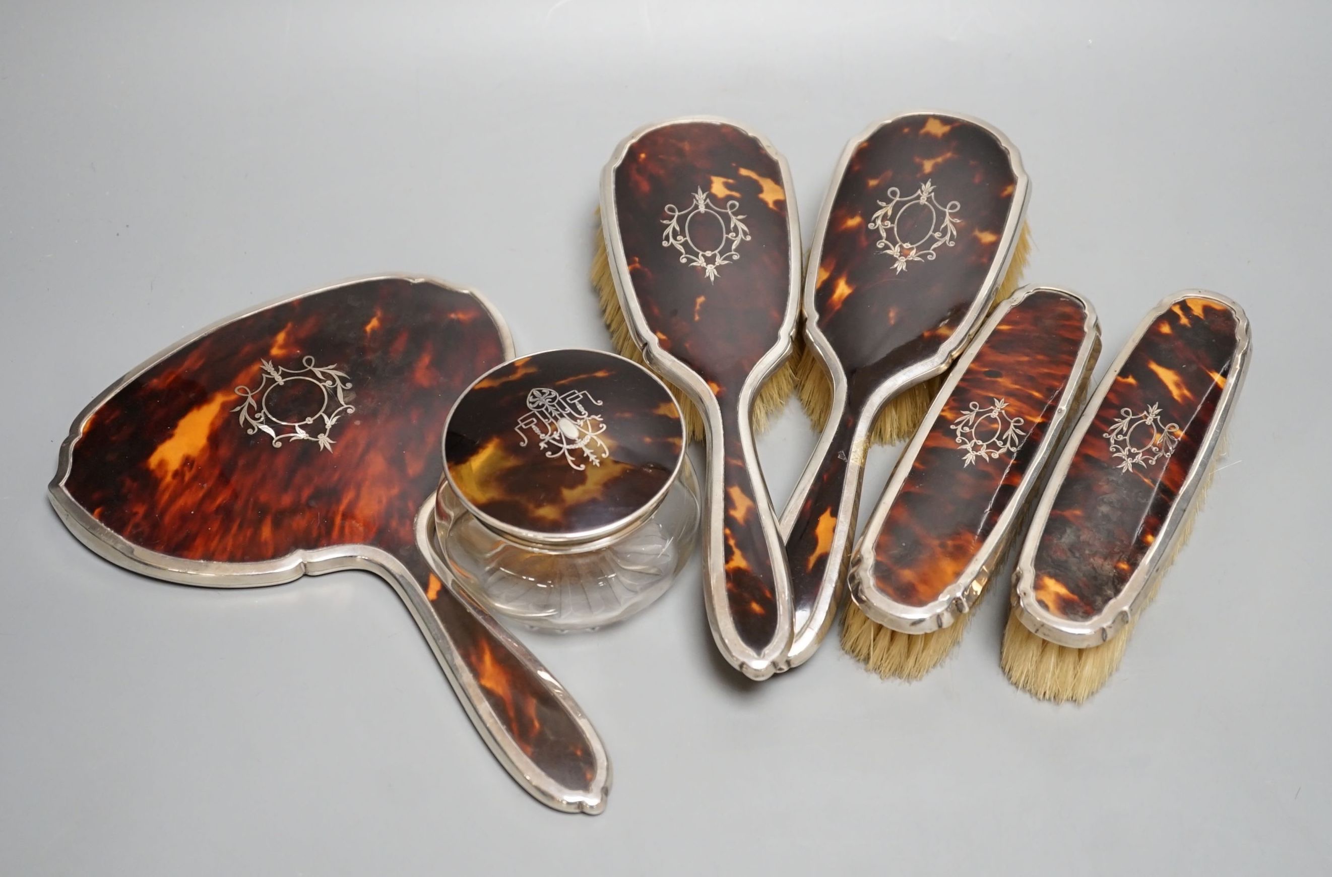 A George V silver and tortoiseshell mounted mirror and brush set, Birmingham, 1928 and a similar powder jar.